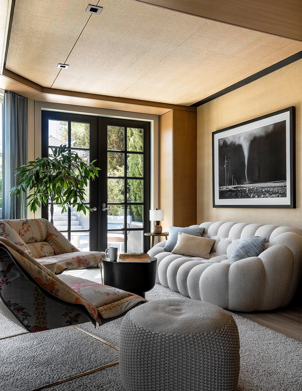 Cozy living room with plush seating, large windows, and a striking black-and-white artwork.