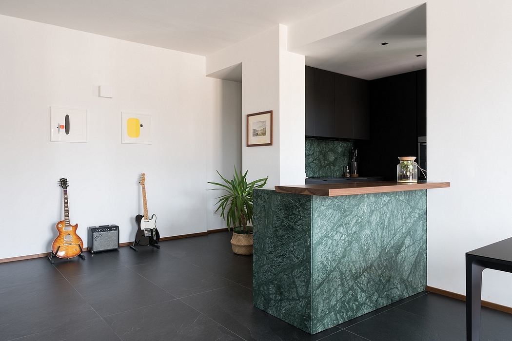Open-concept kitchen with green marble island, wooden countertop, and electric guitars in living area.