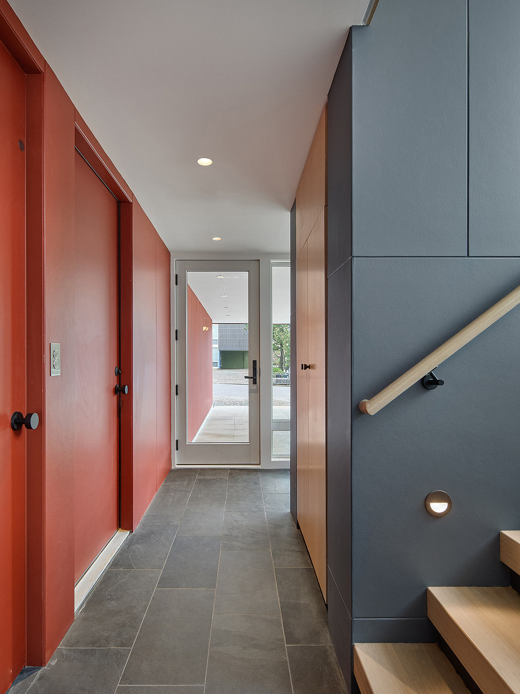 Modern hallway with bold red walls, gray tile floor, and built-in cabinetry.