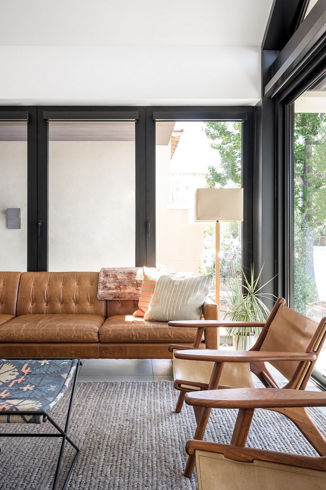 Spacious living room with large leather sofa, wooden armchair, and floor lamp.