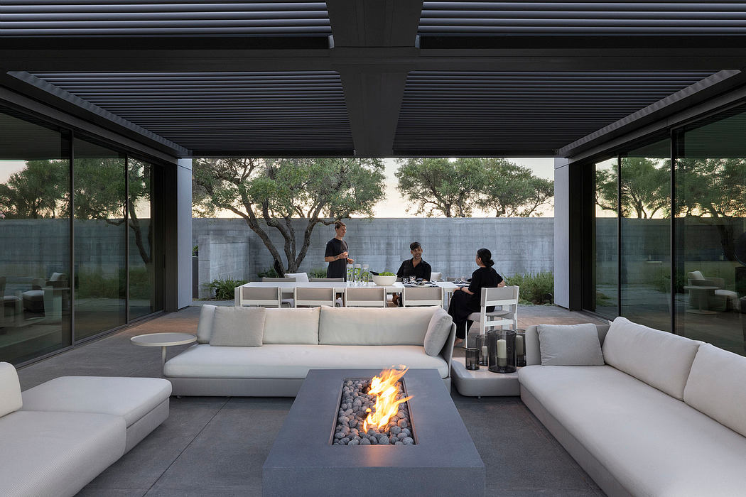 Sleek modern patio design with glass walls, recessed lighting, and a stone fire pit.