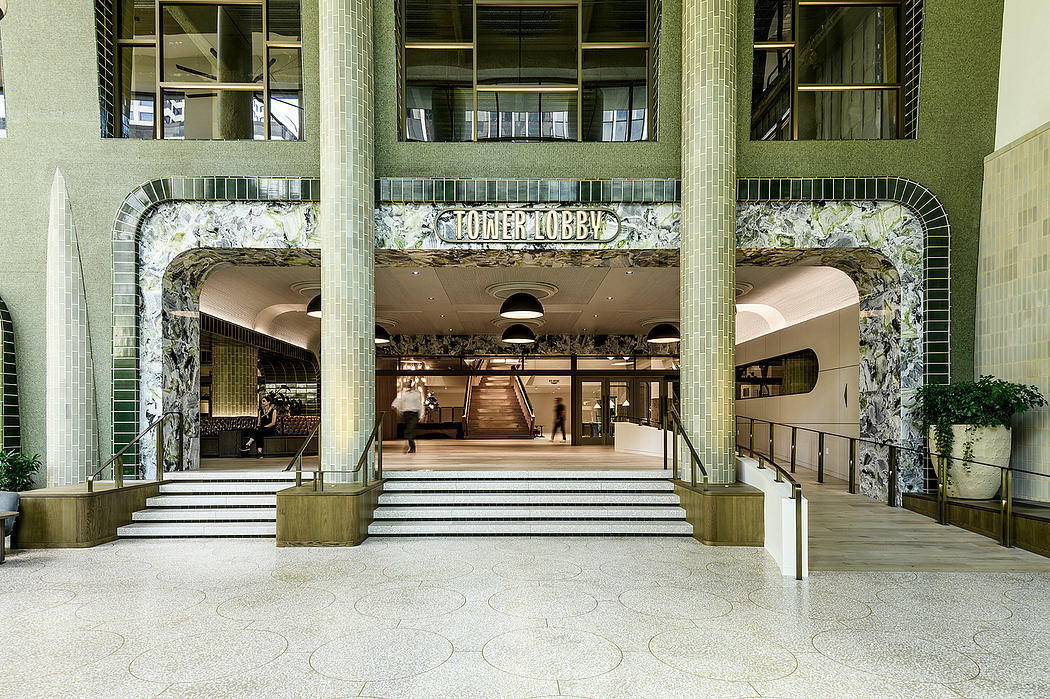 Grandiose Art Deco lobby with ornate stone archways, tiered steps, and decorative lighting.