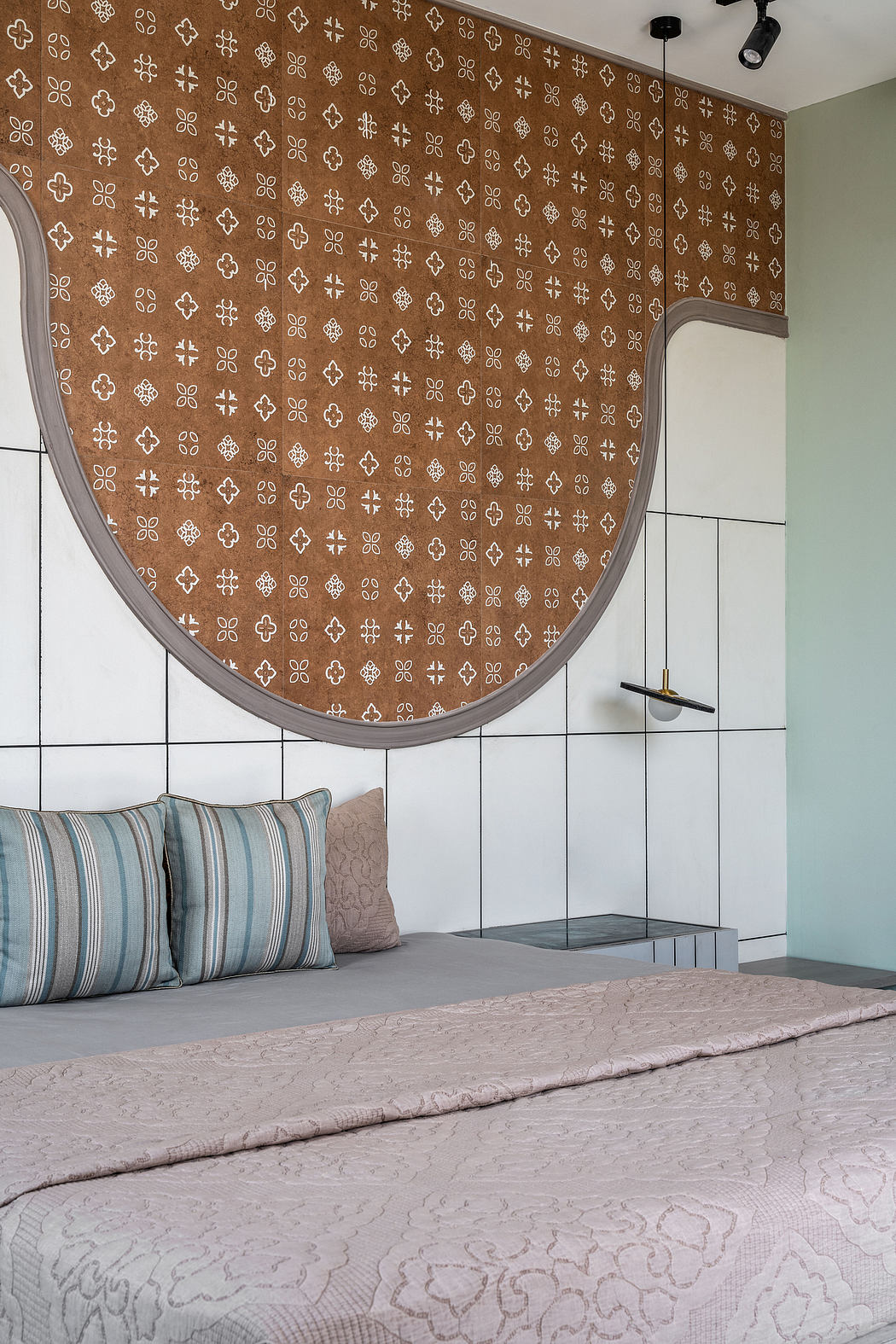 The room features a curved, textured wall with a distinctive floral pattern, complemented by minimalist furnishings and neutral tones.