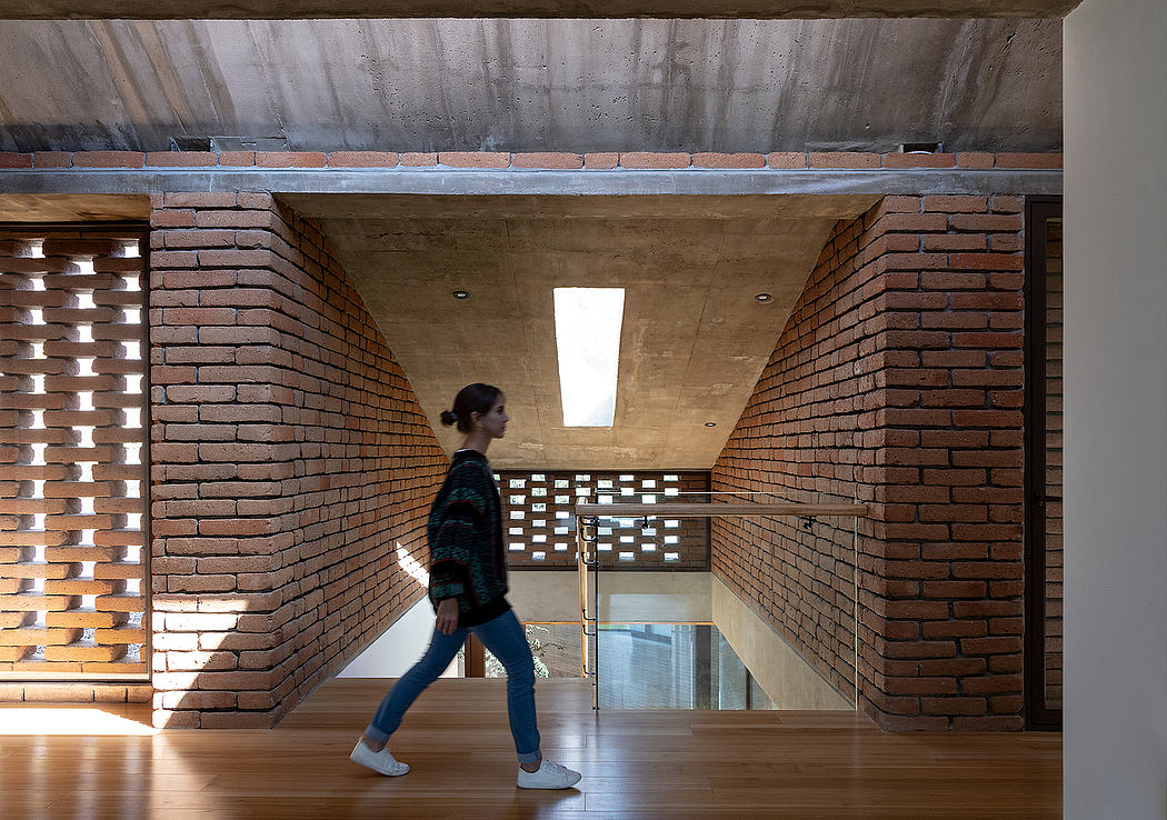 Brick-clad interior with concrete ceiling and wooden floor; person walking through narrow space.