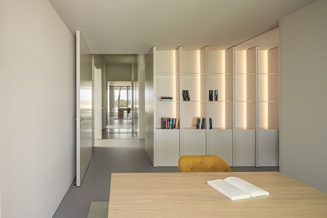 Minimalist interior with sleek built-in shelving units and a book-filled workspace.