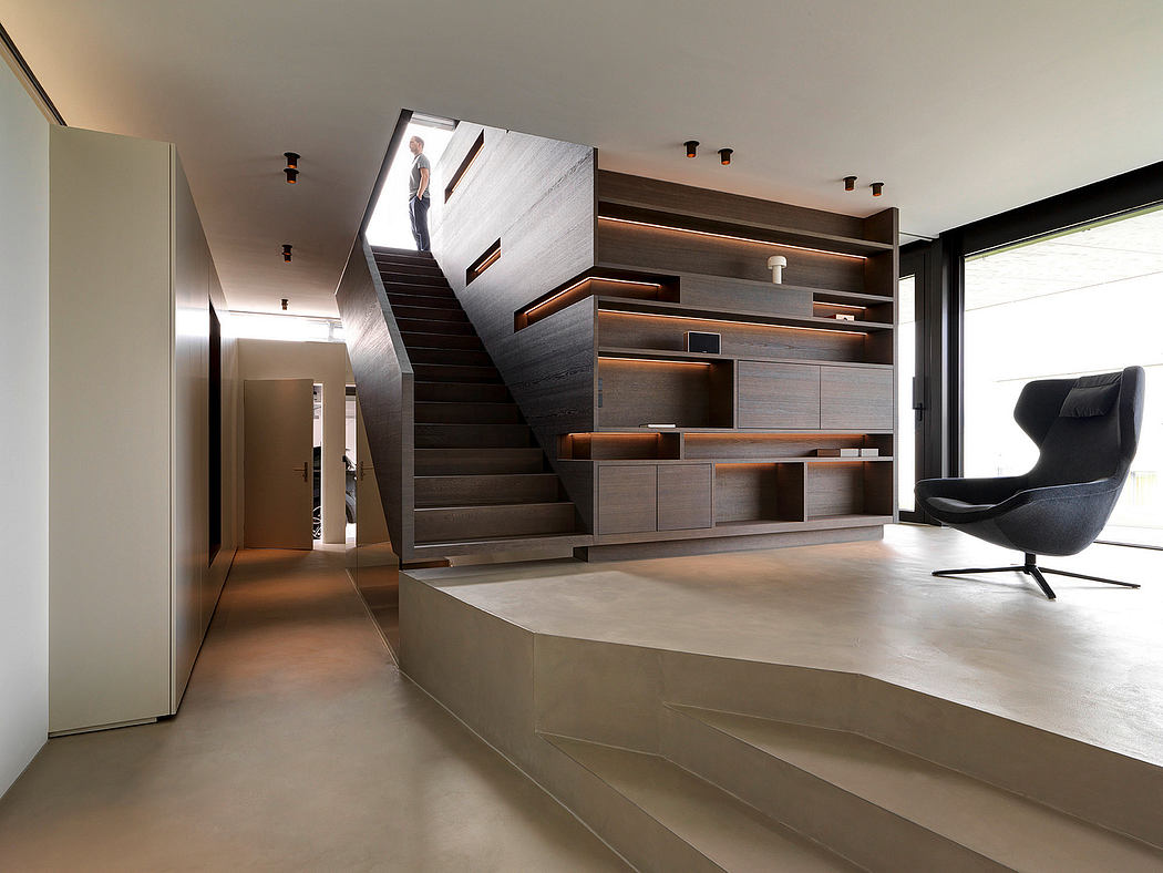 A modern, minimalist interior with a striking staircase, shelving, and lighting design.