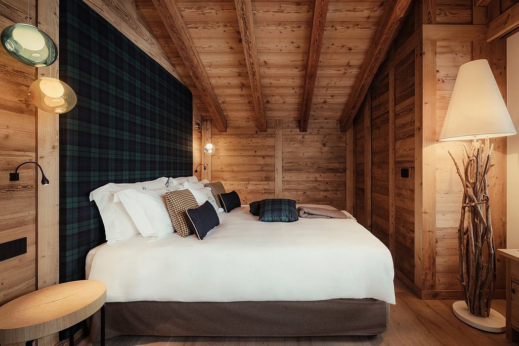 Rustic wood-paneled bedroom with plaid headboard, modern lamps, and textured pillows.