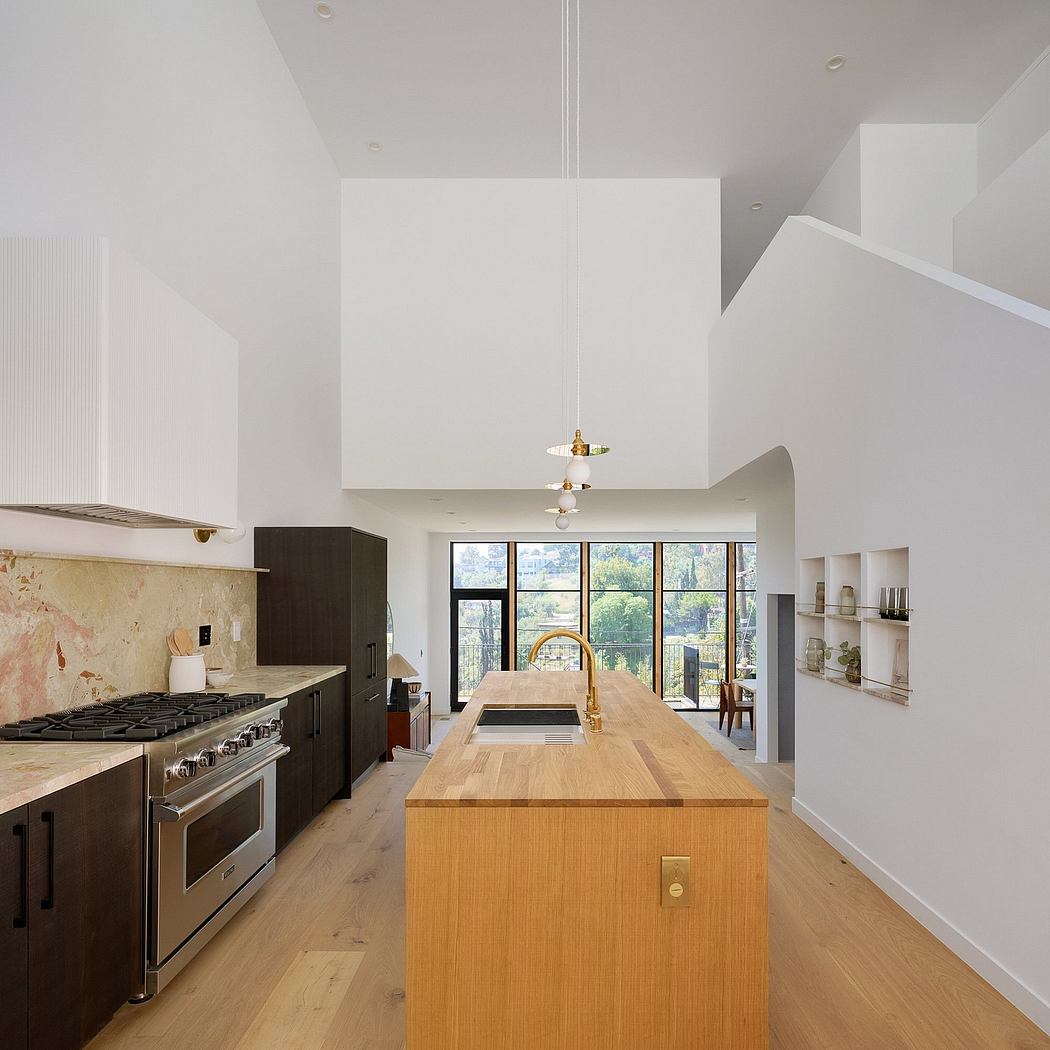 Spacious modern kitchen with high ceilings, large windows, and a wooden island with a gold faucet.