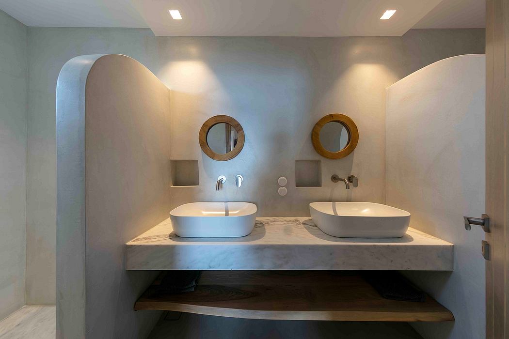 Elegant double vanity with marble countertop, modern sconces, and round mirrors.