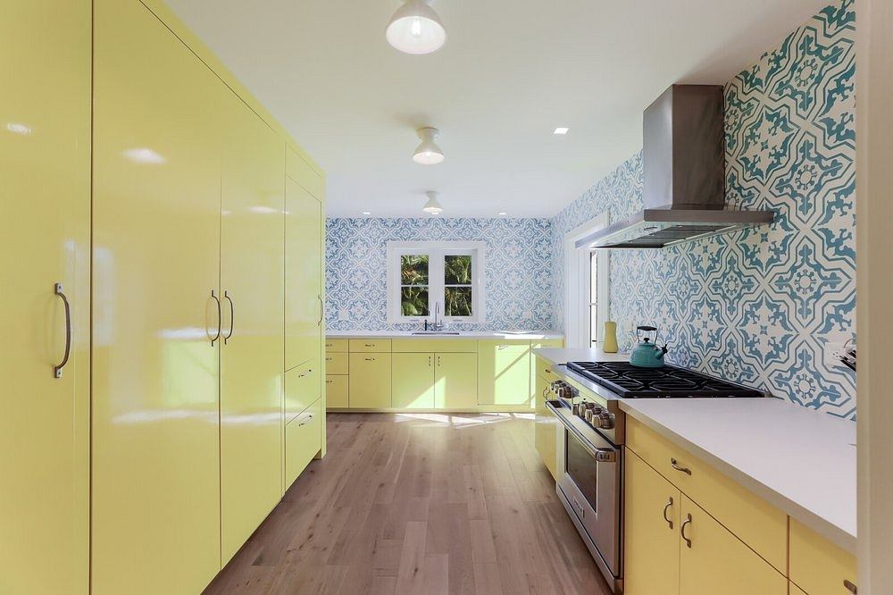 Bright, open kitchen with yellow cabinetry, patterned tile walls, and hardwood flooring.
