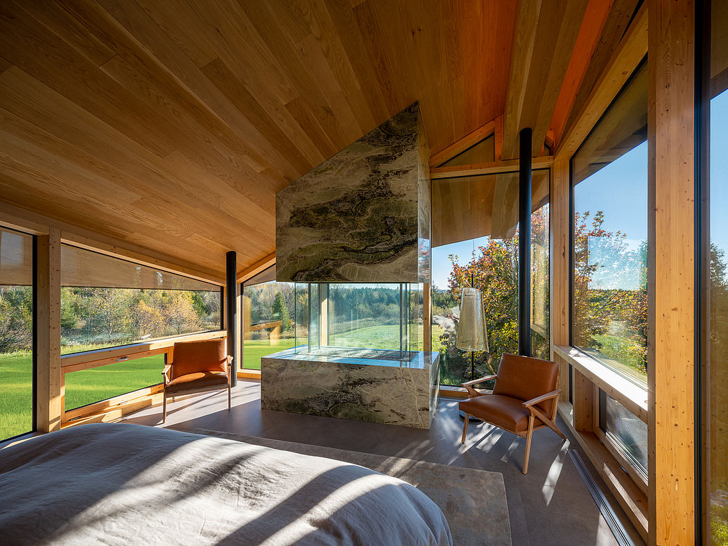 Spacious wooden cabin with a large window overlooking a lush, green landscape.