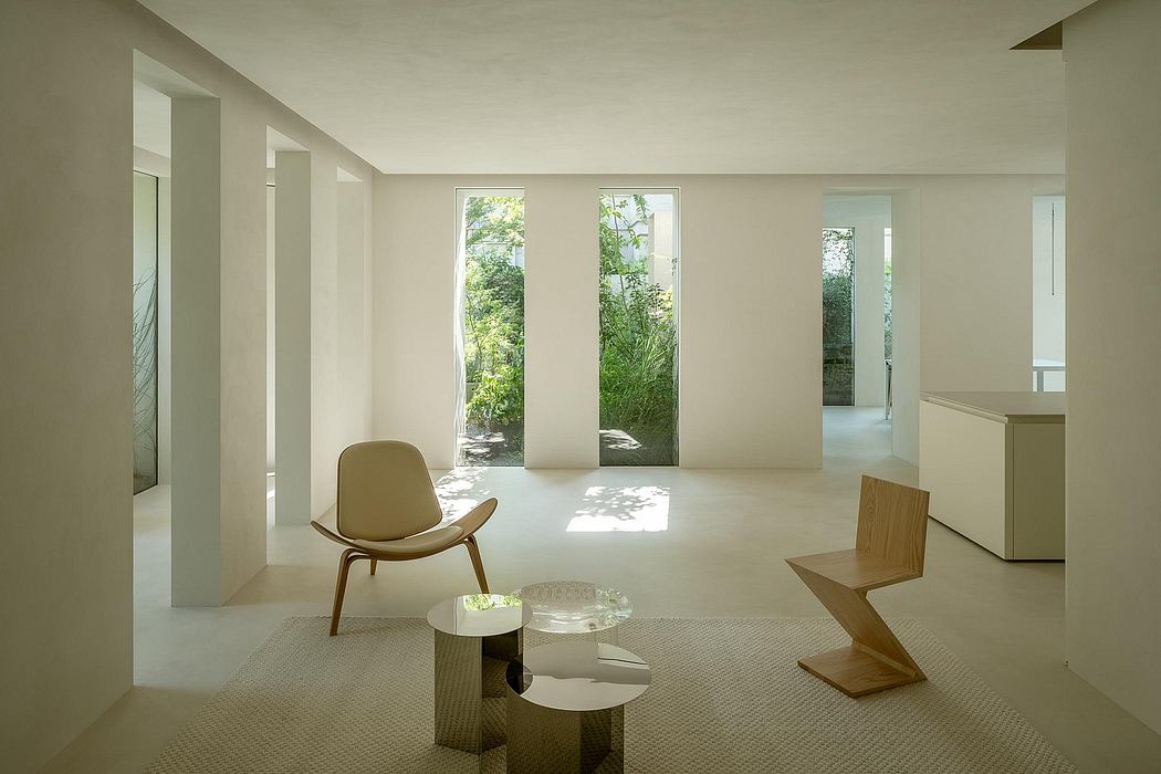 Minimalist interior with floor-to-ceiling windows, neutral tones, and a modern lounge chair.