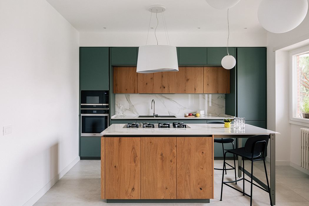 Modern kitchen with green cabinets, wooden island, and marble countertops.