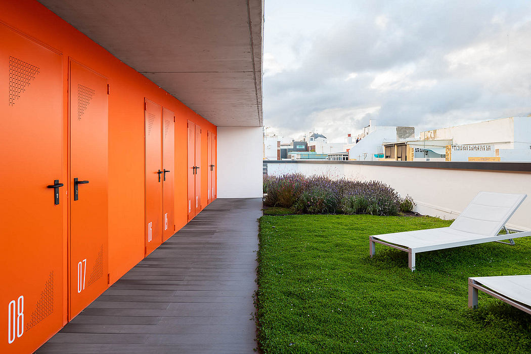 Vibrant orange lockers line a modern corridor leading to a lush green lawn and seating.