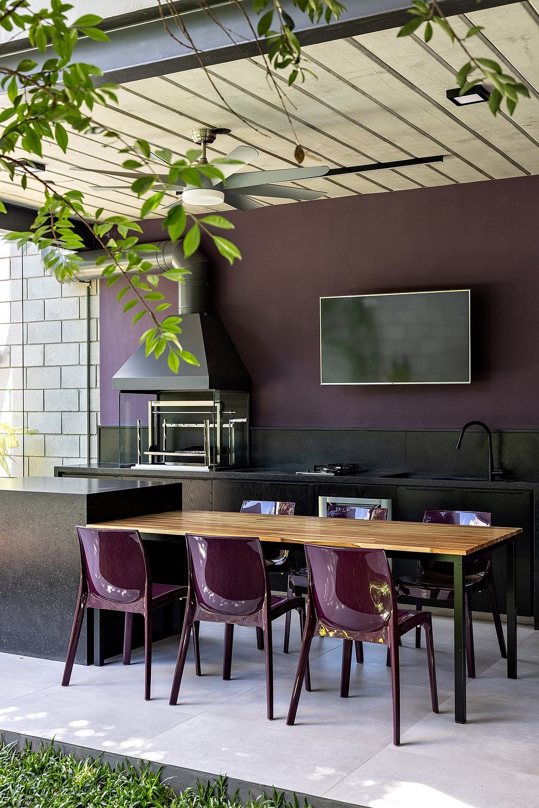 Contemporary dining space with sleek wooden table, plum chairs, and black accent walls.