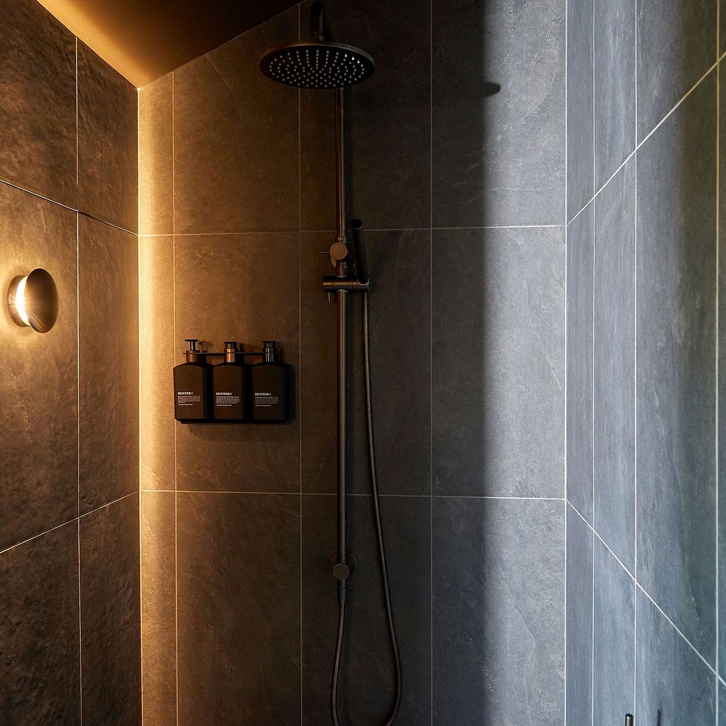Modern bathroom with sleek, monochromatic tiles and a minimalist showerhead fixture.