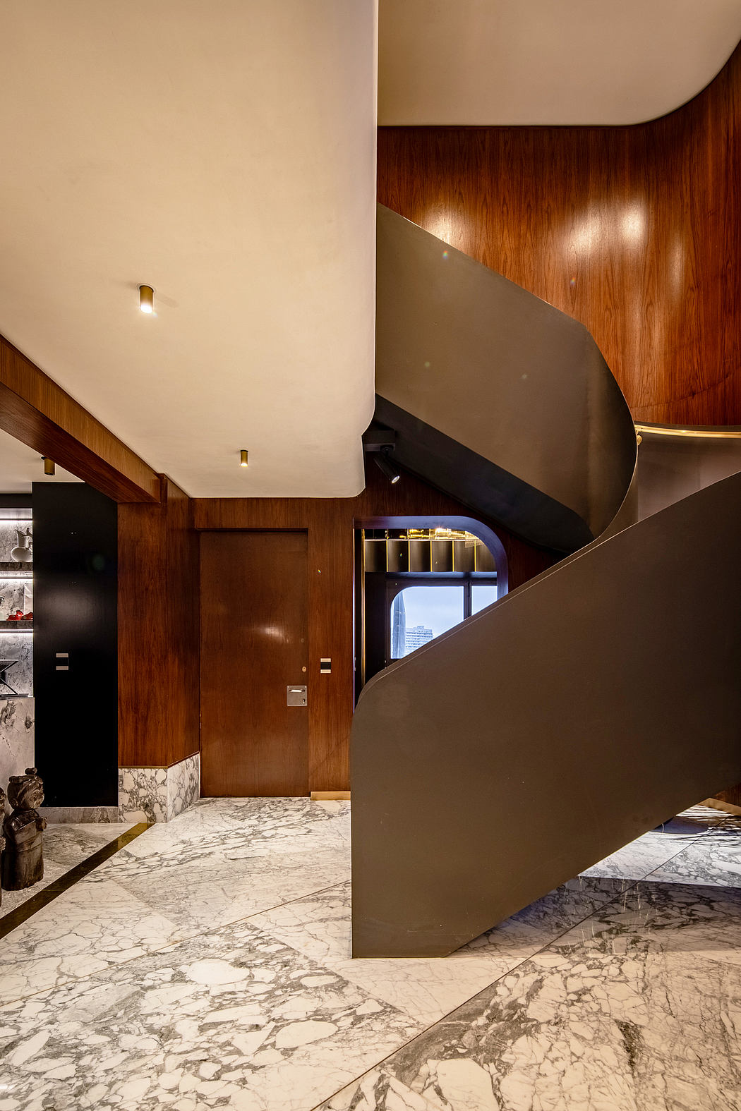 Striking architectural interior with curved wooden walls, marble floors, and recessed lighting.