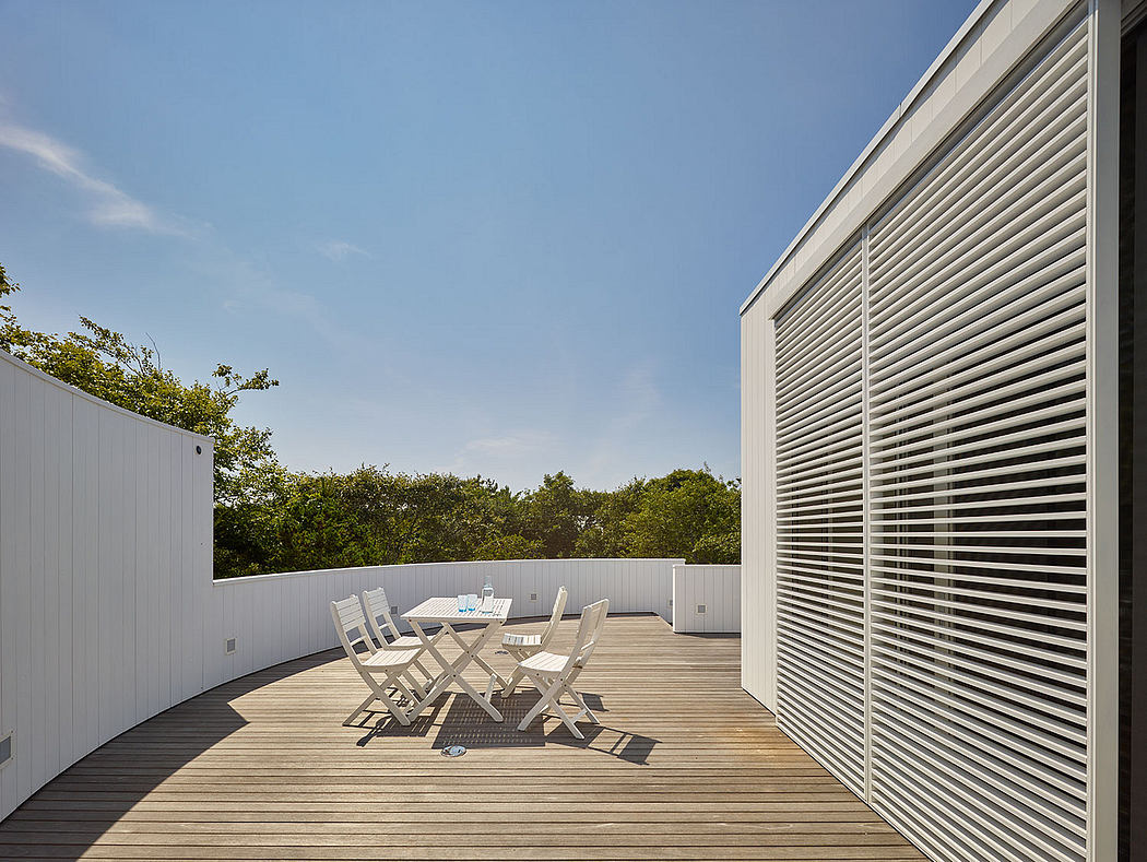 Expansive outdoor deck with slatted walls, offering a tranquil dining area amidst lush foliage.
