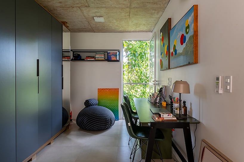 A modern, open-concept room with concrete ceiling, vibrant artwork, and functional furnishings.
