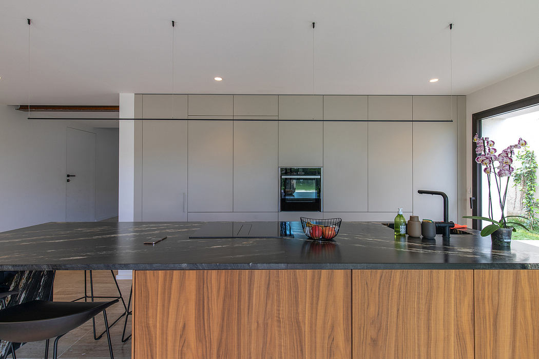 Sleek, modern kitchen with minimalist gray cabinetry, dark granite countertops, and warm wood accents.