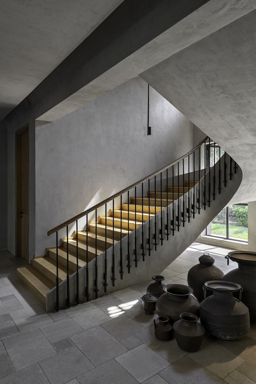 A striking interior design with a dramatic concrete staircase and pottery accents.