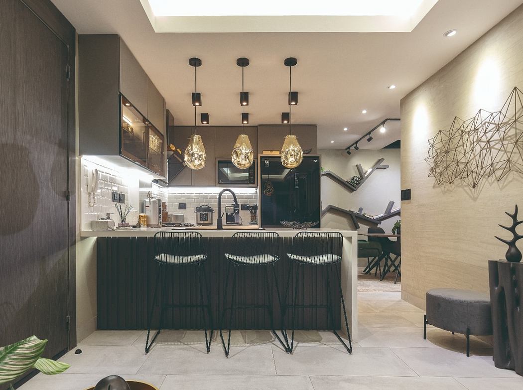 Modern kitchen with sleek black cabinetry, pendant lighting, and a cozy seating area.
