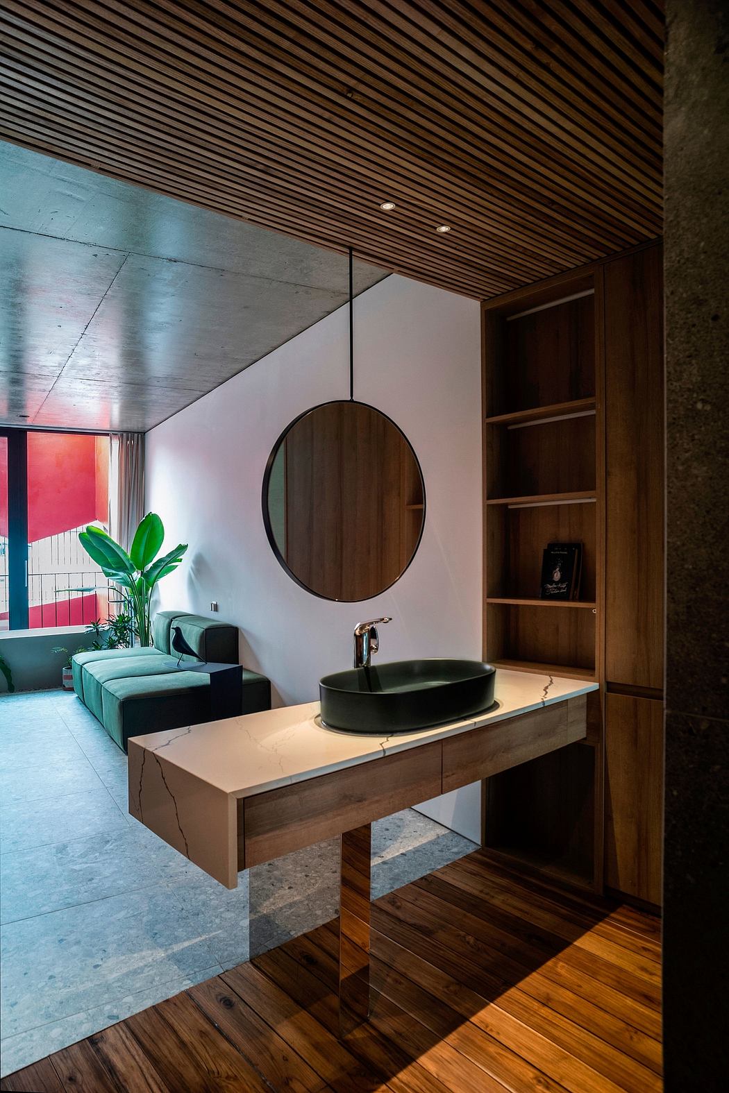A modern bathroom design featuring a wooden ceiling, circular mirror, and green vessel sink.