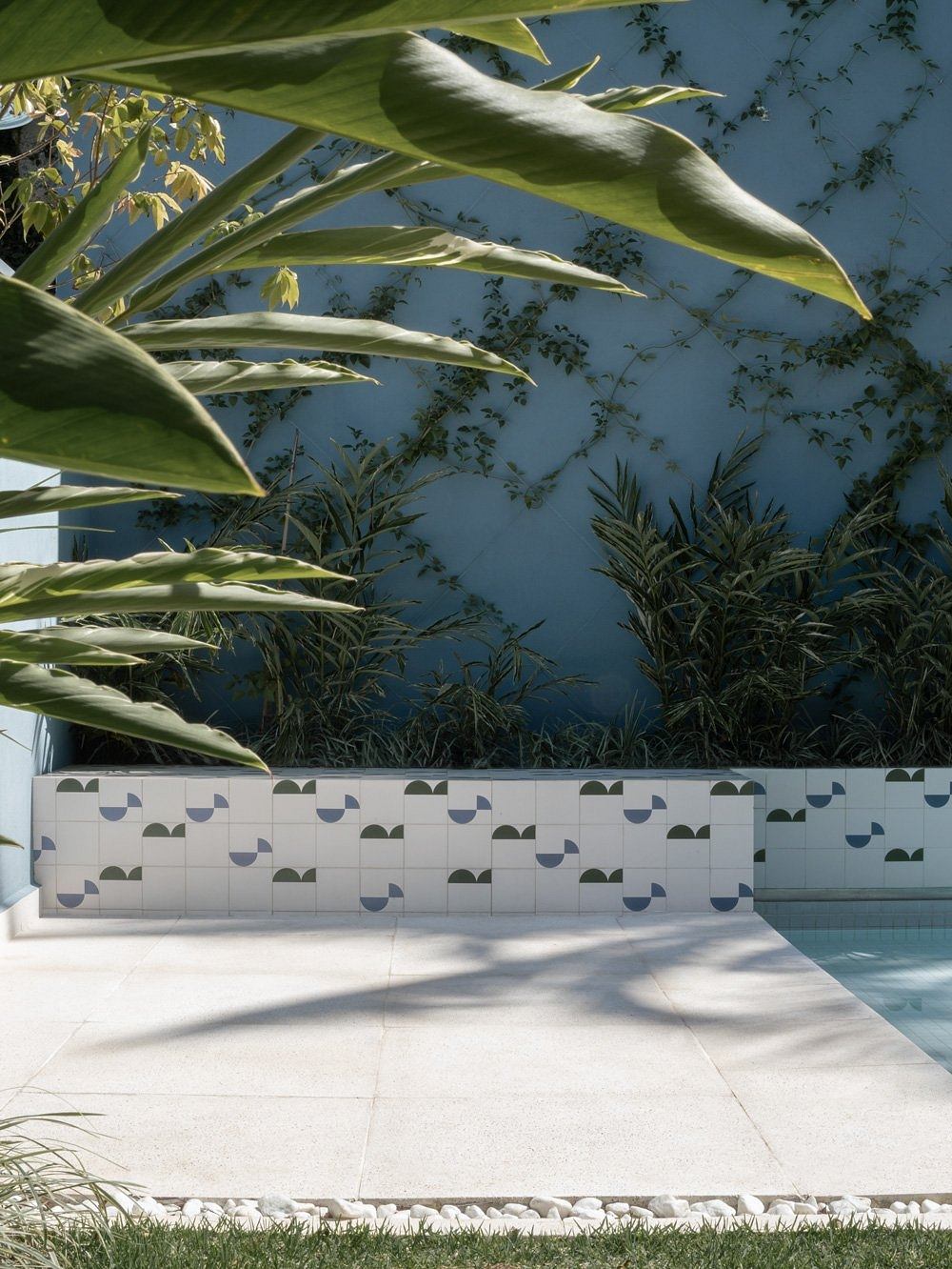 A modern pool area with stylized tiled walls and surrounding lush greenery.