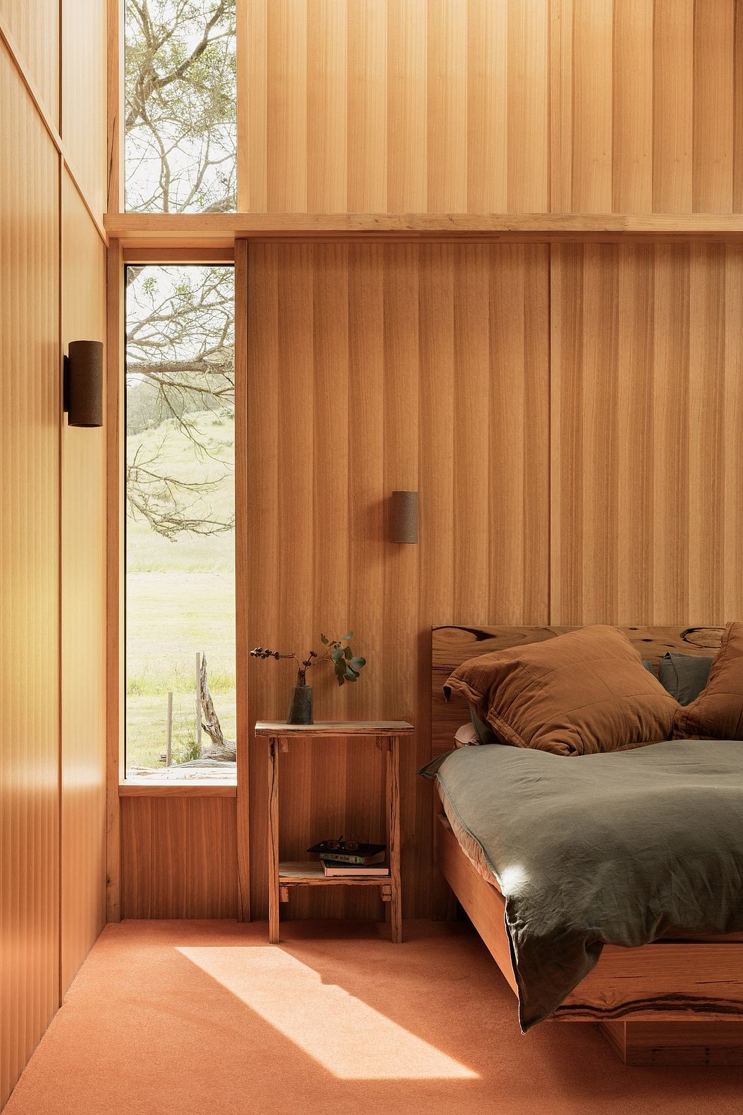 Cozy wooden bedroom with large window overlooking lush greenery outside.