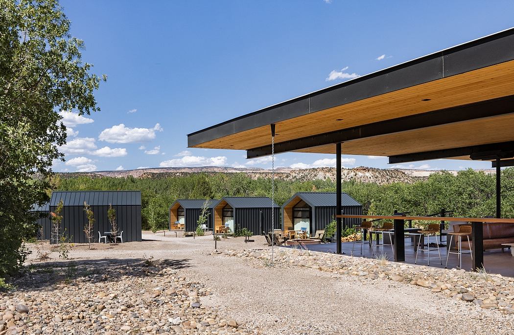 Modern outdoor seating area with a wooden roof, black accents, and desert landscape.