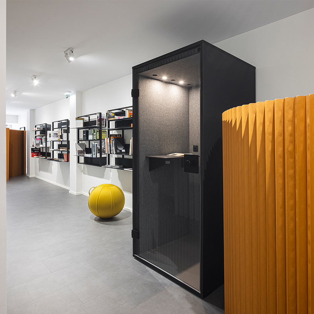 Modern interior with sleek black shelving units, a bright yellow cushioned chair, and recessed lighting.