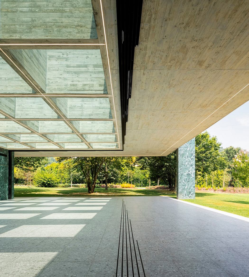 Minimalist architectural design with glass ceiling, concrete floor, and lush greenery.