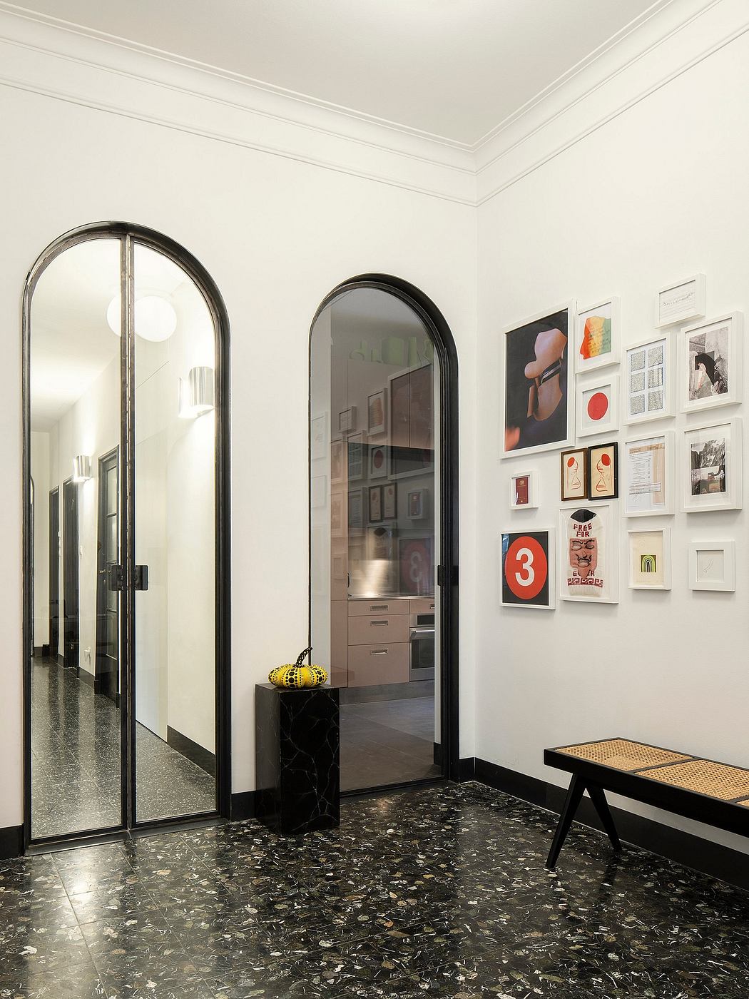 The image shows a stylish entryway with arched mirrors, artwork, and a terrazzo floor.