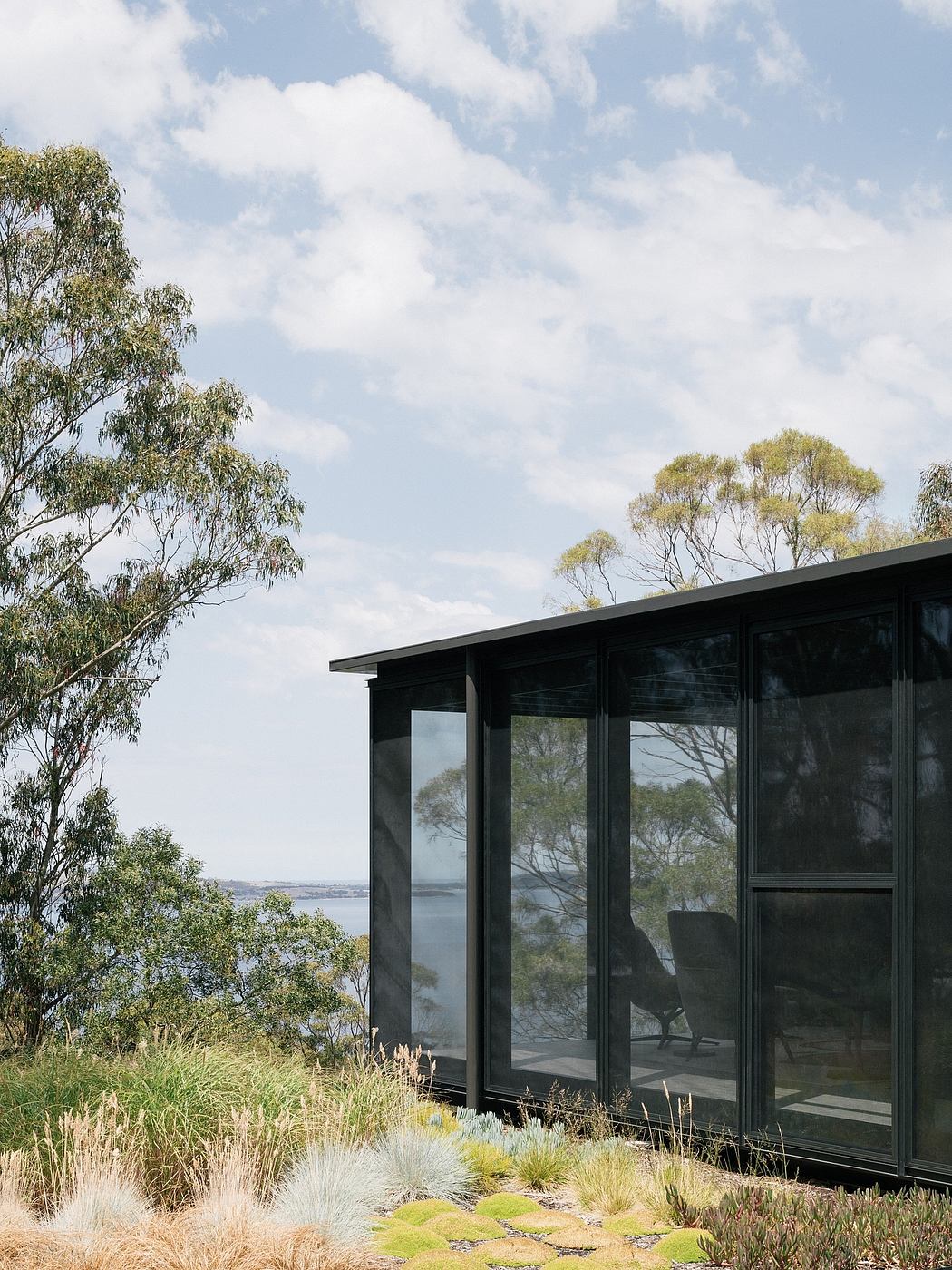 A modern glass-enclosed structure overlooking a picturesque landscape, featuring a lush natural setting.
