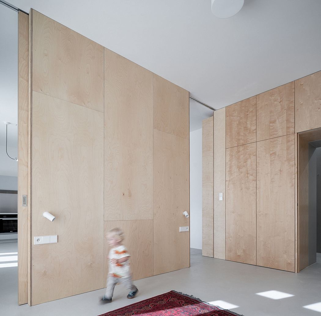Interior features wood-paneled walls, minimal furnishings, and a blurred person walking across a rug.