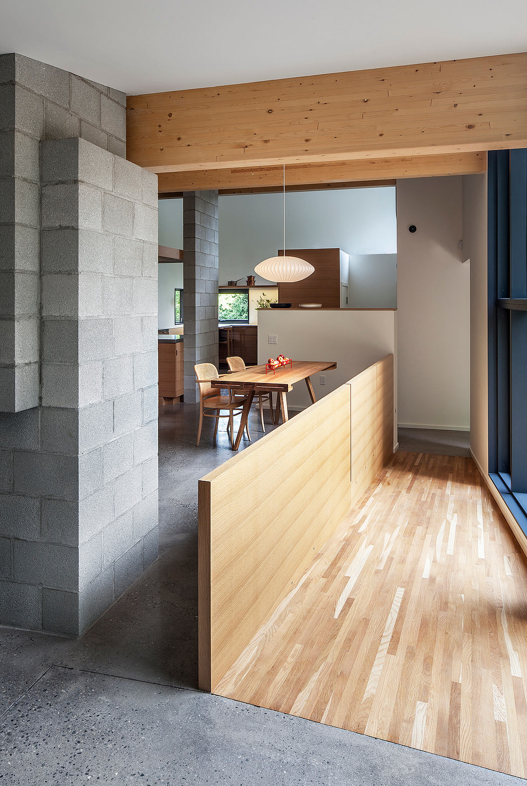 A modern, minimalist interior featuring exposed concrete walls, wood paneling, and a sleek dining area.