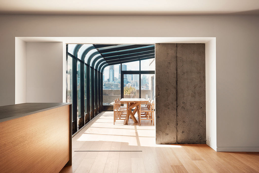 Modern open-concept interior with glass walls, wooden furniture, and cityscape view.