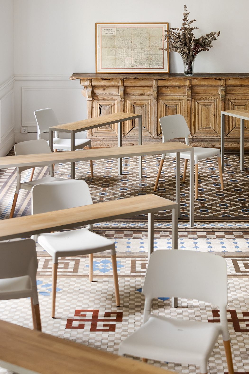 Rustic dining room with intricate tiled floor, wooden furniture, and framed map.