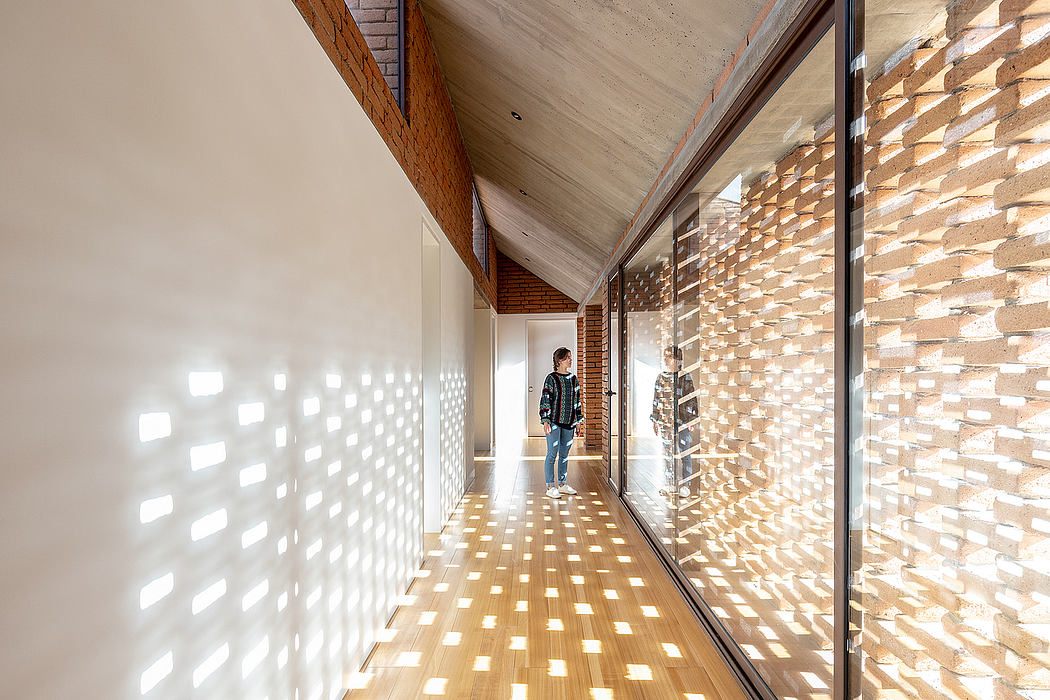 An expansive, sunlit hallway with a textured brick wall, creating a striking geometric pattern.
