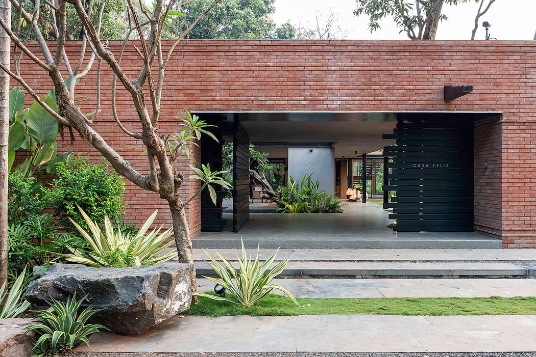 A modern, brick-clad structure with a lush, tropical landscaped entrance.