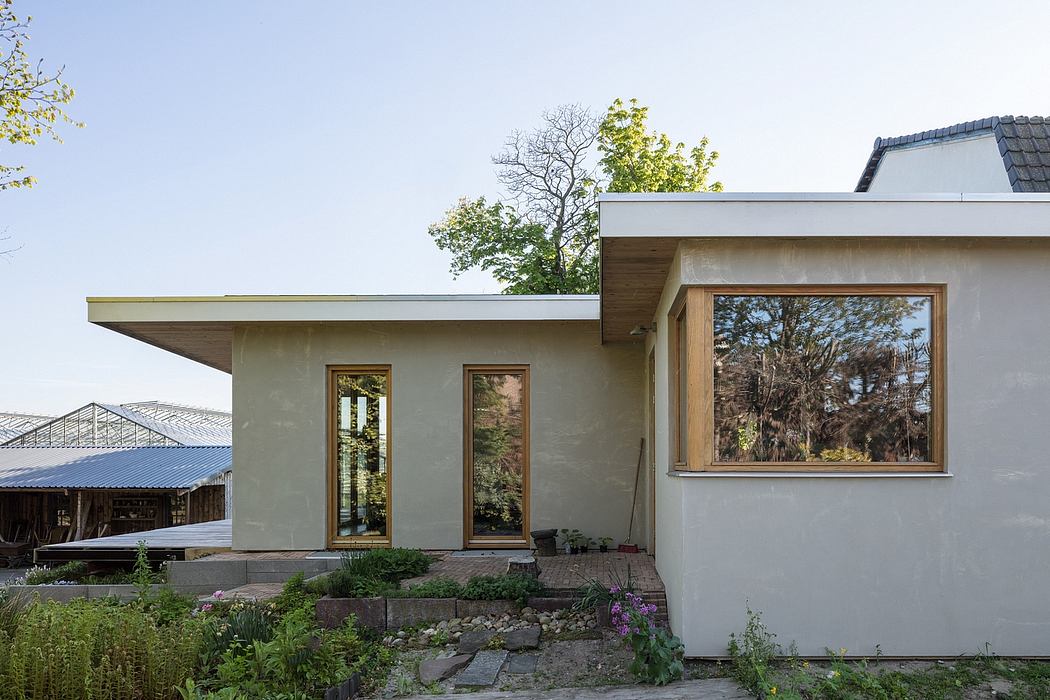 A modern, minimalist house with large windows, wood trim, and a landscaped garden.