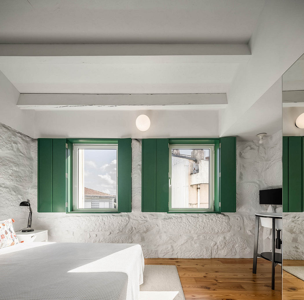 Minimalist bedroom with white walls, green window frames, and wooden flooring.