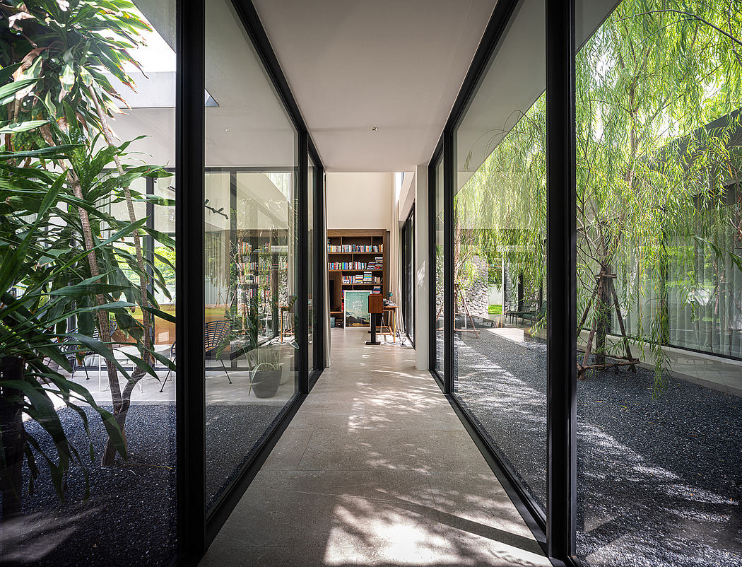 Minimalist hallway with lush greenery visible through large windows and glass doors.