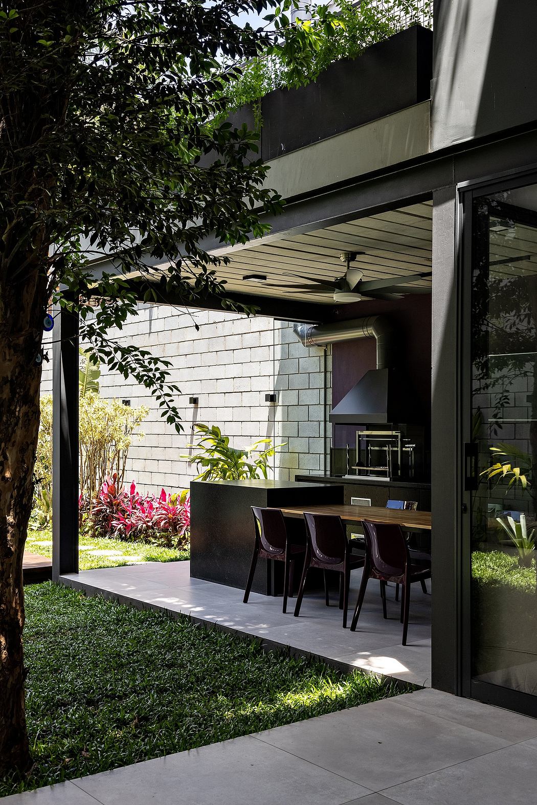 A modern outdoor kitchen area with a sleek, minimalist design and lush greenery surrounds.