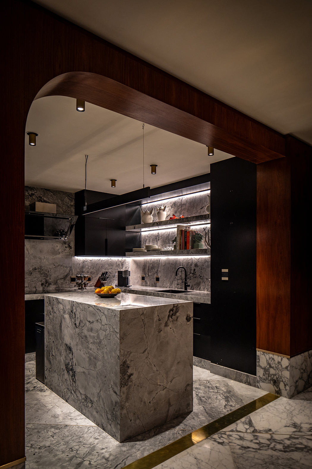 Sleek, modern kitchen with dark marble countertops, recessed lighting, and wooden accents.