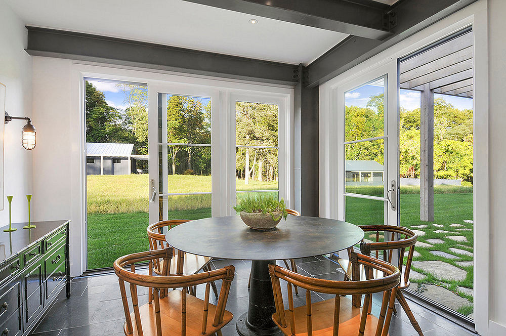 Contemporary, open-plan dining area with floor-to-ceiling windows, modern furnishings, and lush outdoor views.