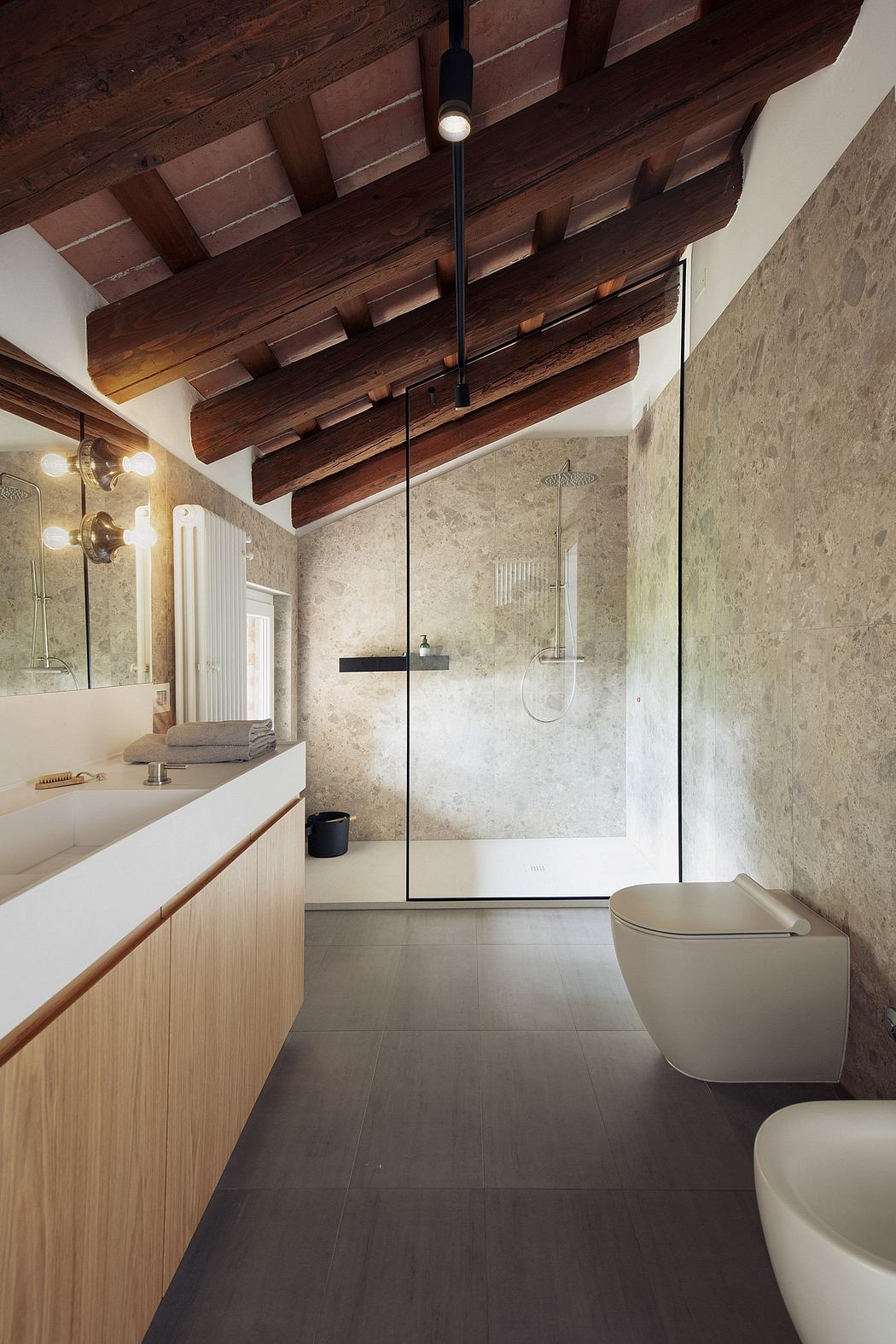 Rustic wooden ceiling beams, clean minimalist vanity, and modern shower enclosure.
