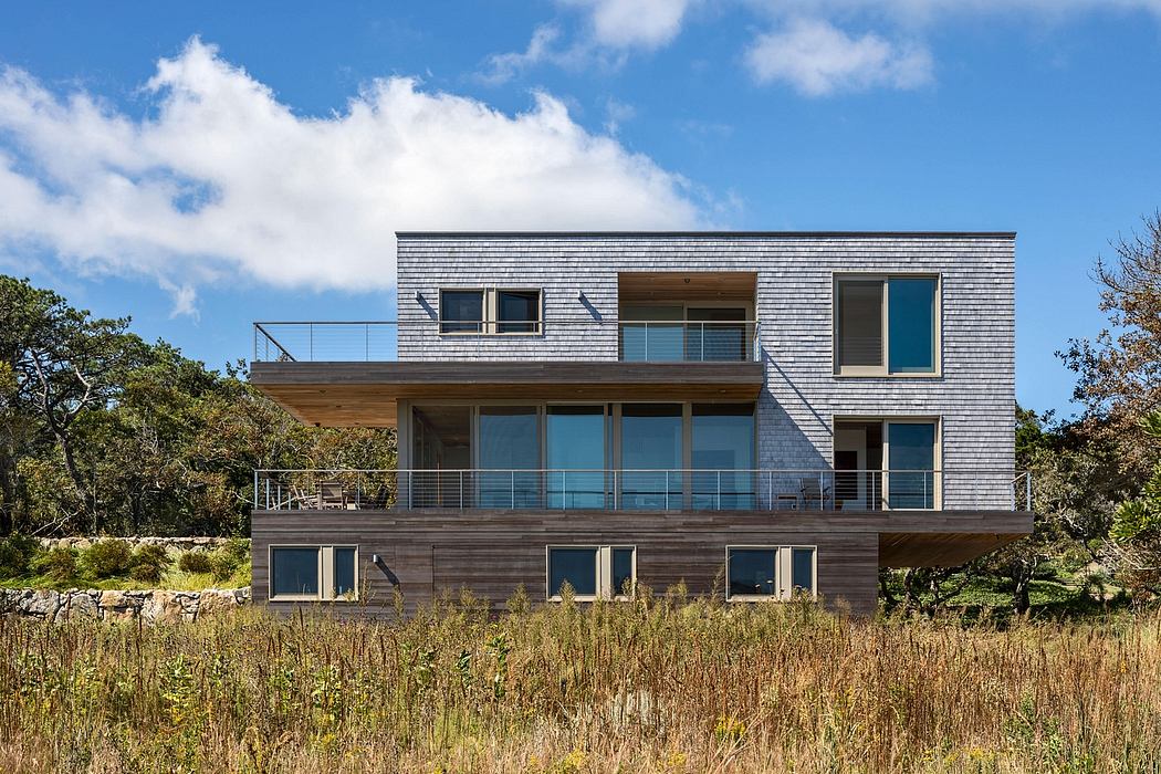 Sleek, modern, wood-clad residence with expansive glass windows and balconies.