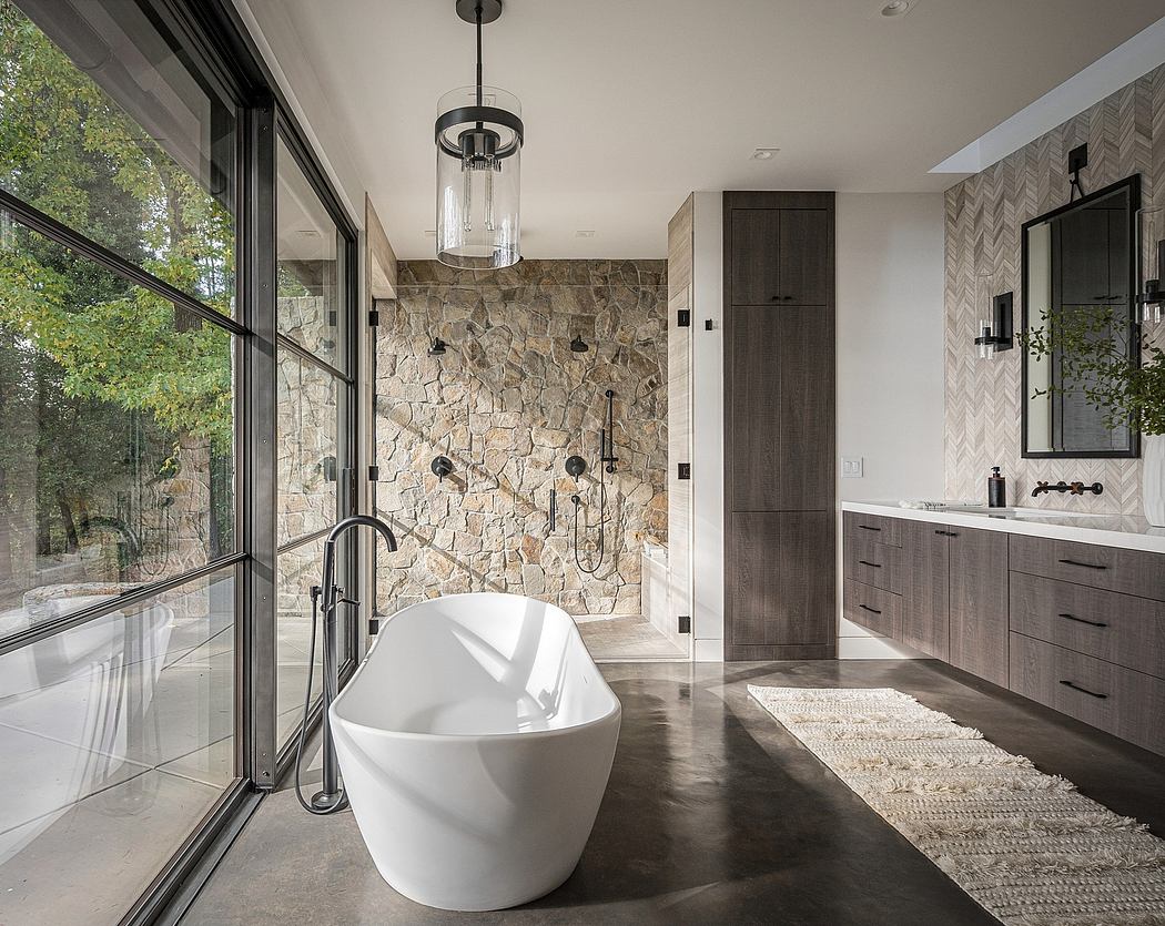 Elegant modern bathroom with stone wall, freestanding tub, and sleek cabinetry.