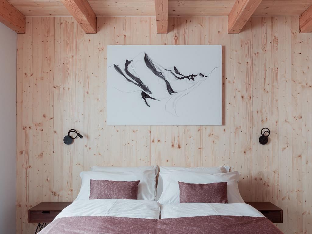 Cozy wooden cabin bedroom with abstract painting and minimalist decor elements.